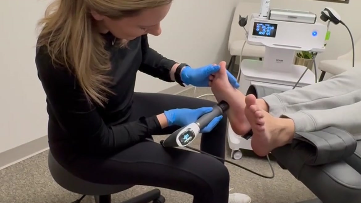 Dr. Amanda Myers treating a patient's foot with a handheld therapy device during neuropathy care at True Health Chiropractic in Lombard, IL